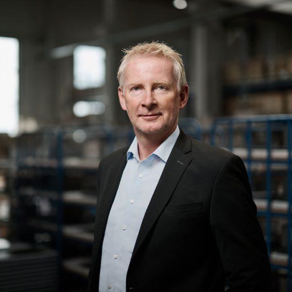 Ein CEO in einem Anzug steht in einem Lagerhaus.