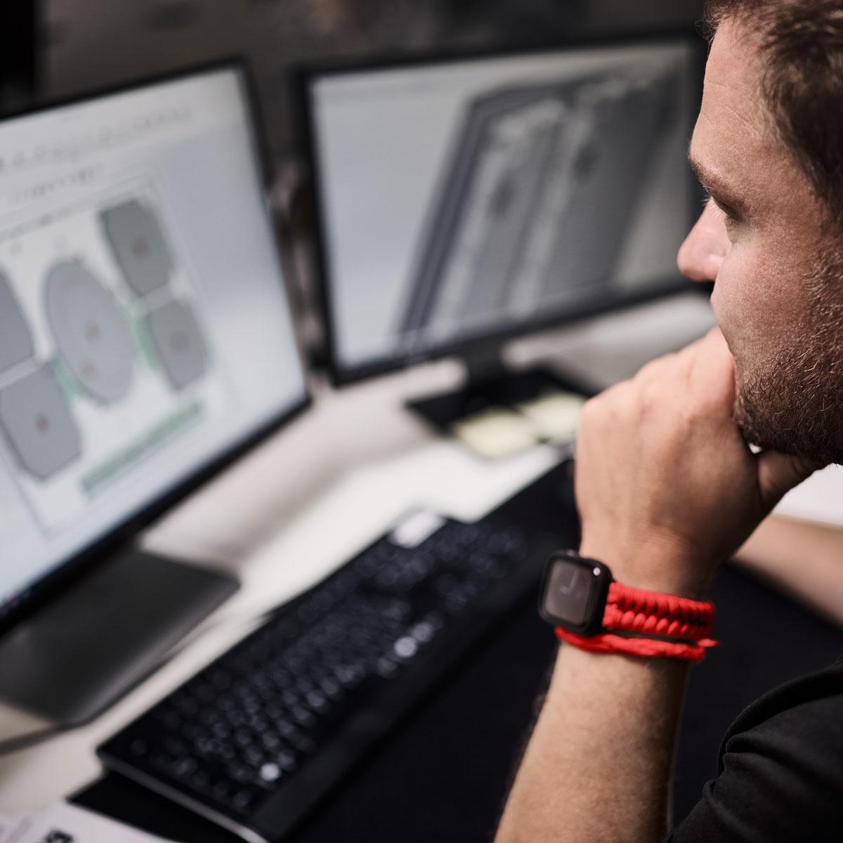 Ein Ingenieur arbeitet vor zwei Monitoren an einem Computer